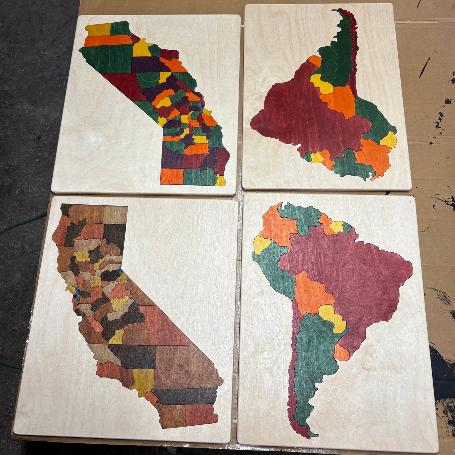 Four wooden maps of South America and California with colorful patterns.