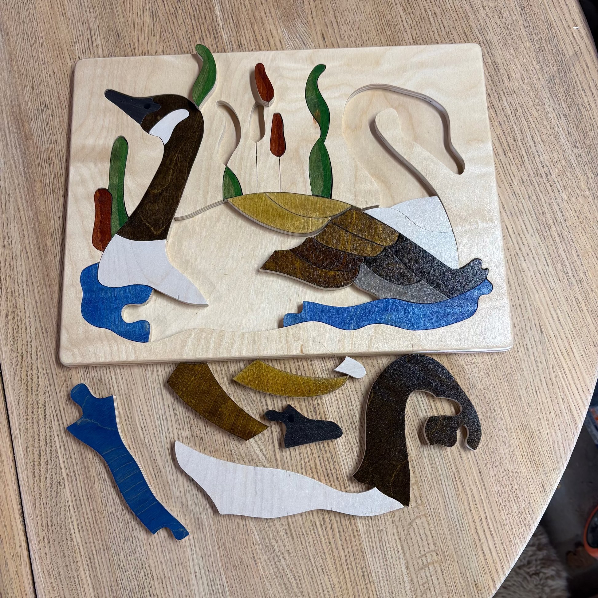 Wooden puzzle with Canada Geese swimming on a tule pond