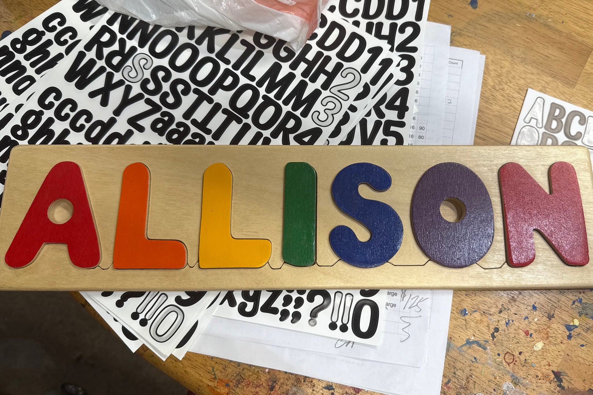 Wooden name puzzle with colorful letters spelling 'ALLISON' on a wooden surface.