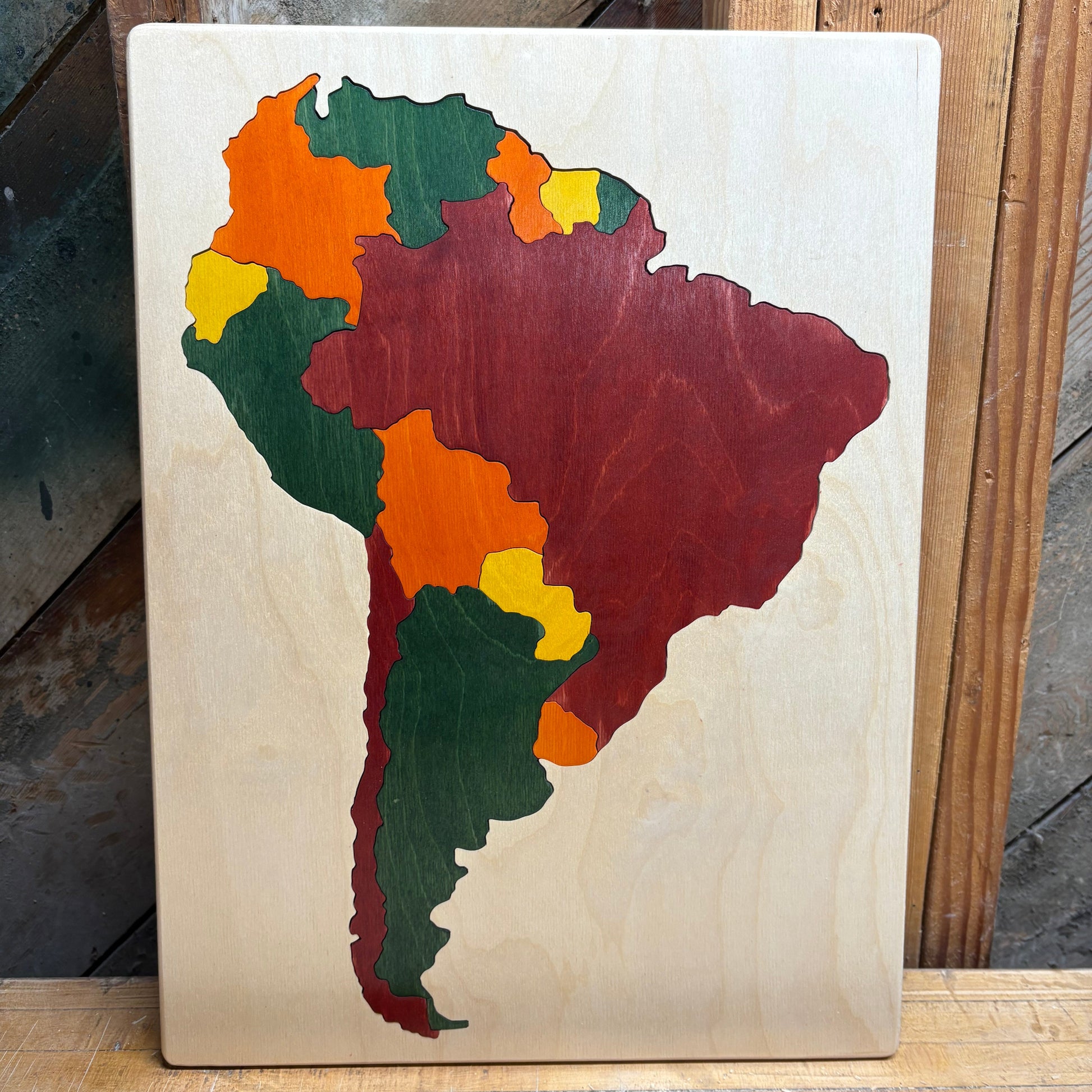 Wooden puzzle of South America with colored pieces on a wooden surface