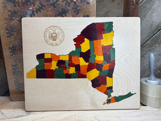 Wooden puzzle in the shape of a map of New York with colorful stained puzzle pieces.