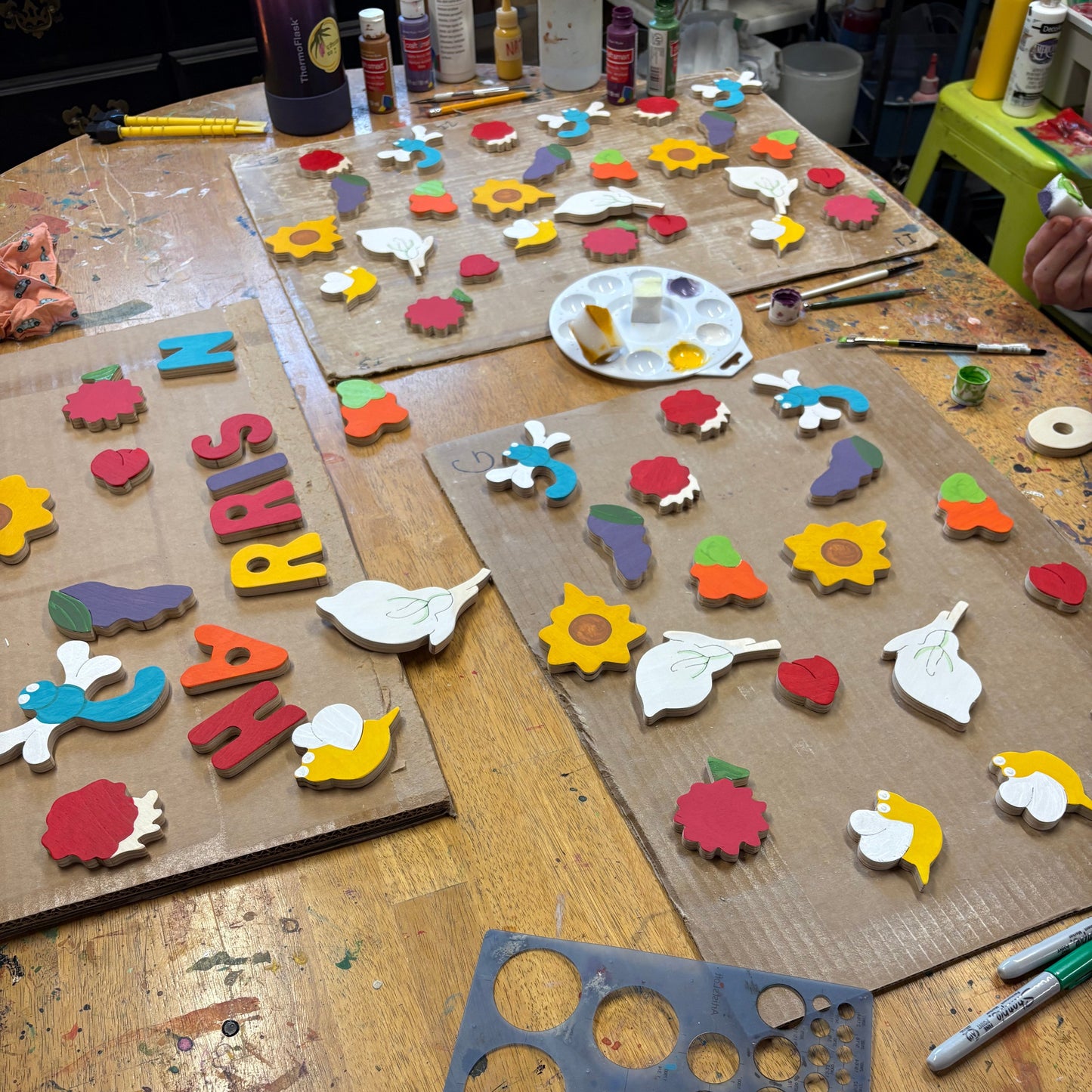 Wooden craft items including letters, shapes, and a paint palette on a wooden table.