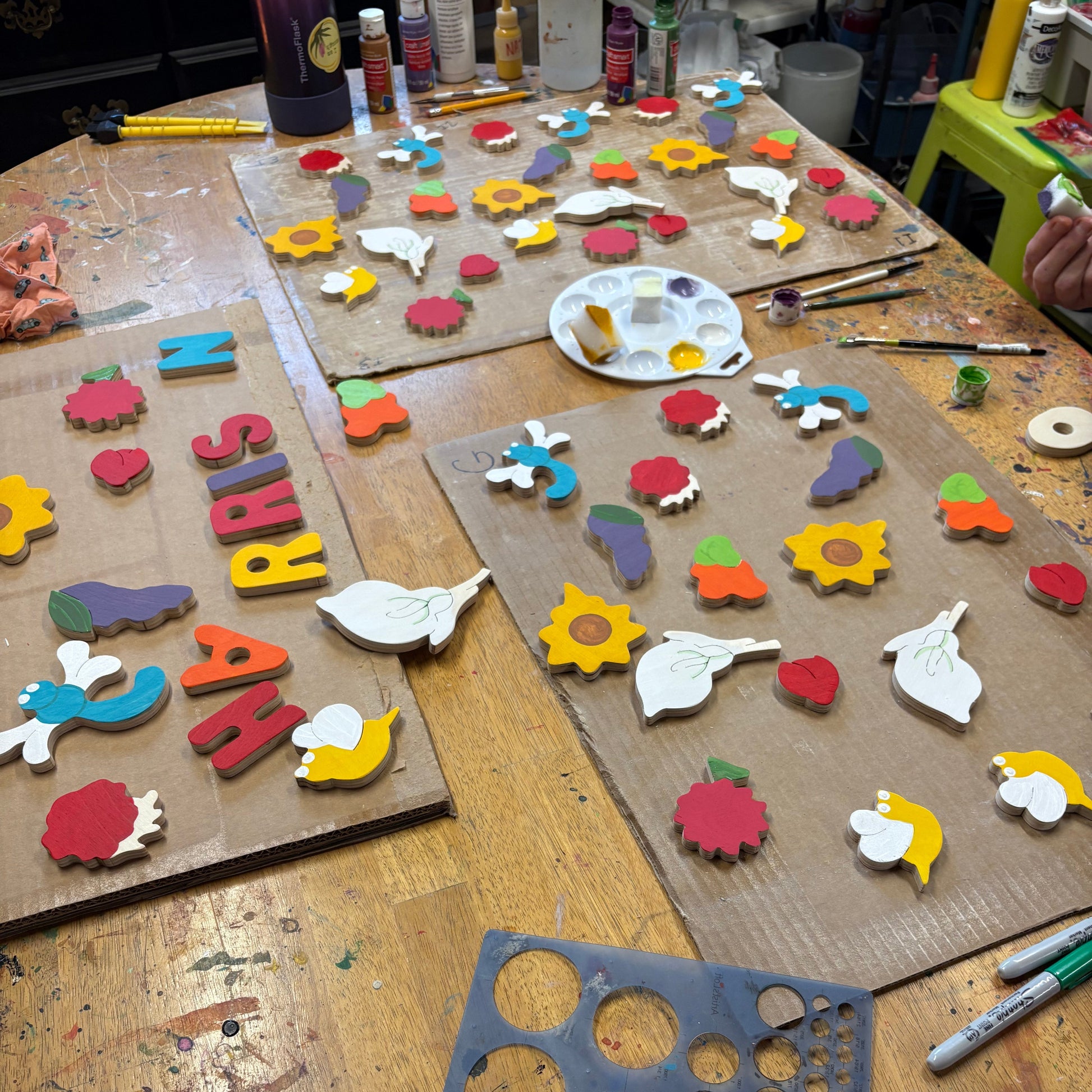 Wooden craft items including letters, shapes, and a paint palette on a wooden table.