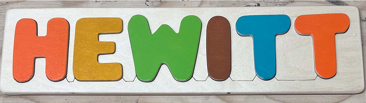 Colorful wooden letters spelling 'HEWITT' on a wood puzzle