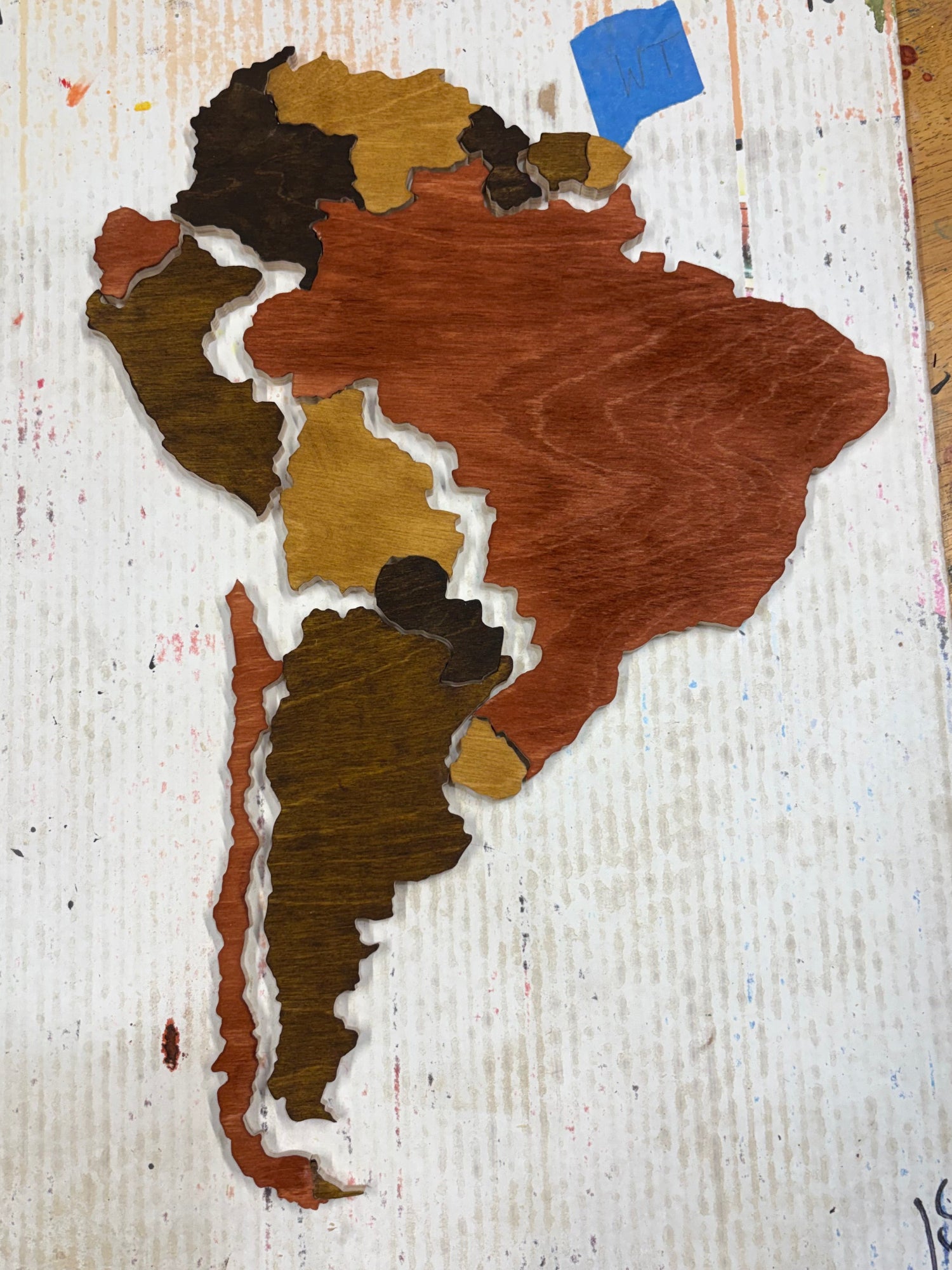 Puzzle Map of South America made with brown, black, and beige colors on a textured surface.