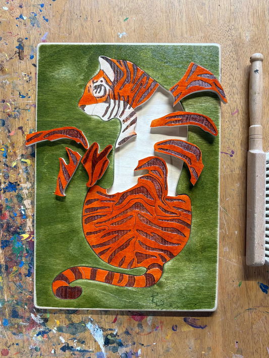 Wooden puzzle piece with a tiger design on a paint-splattered wooden surface